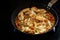 Cooking a creamy chicken ragout with bell pepper and mushroom in a pan on a black stove, copy space