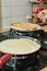 Cooking Crepe Suzette pancakes in frying pan on gas stove. Greases pancakes with butter