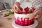 Cooking and decoration of cake with cream. Young woman pastry chef in the kitchen decorating red velvet cake