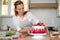 Cooking and decoration of cake with cream. Young woman pastry chef in the kitchen decorating red velvet cake