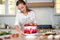 Cooking and decoration of cake with cream. Young woman pastry chef in the kitchen decorating red velvet cake