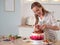 Cooking and decoration of cake with cream. Young woman pastry chef in the kitchen decorating red velvet cake