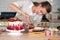 Cooking and decoration of cake with cream. Young woman pastry chef in the kitchen decorating red velvet cake