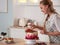 Cooking and decoration of cake with cream. Young woman pastry chef in the kitchen decorating red velvet cake