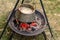 Cooking delicious lunch while camping, an iron pot full of soup brewed over an open fire