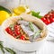 Cooking dinner, raw white trout fish in a baking dish with zucchini, cherry tomatoes on a branch, rosemary, lemon. Delicious heal