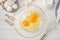 Cooking dough for traditional thin pancakes or crepes. Eggs, flour, salt, sugar in a bowl on a white wooden background. Recipe