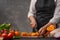 Cooking festive chicken for baking, the chef cuts an orange against a background of vegetables and fruits. Recipe book and