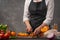 Cooking festive chicken for baking, the chef cuts an orange against a background of vegetables and fruits. Recipe book and