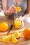 Cooking, food and concept of veganism, vigor and healthy eating - close up of female hand squeeze fresh orange juice