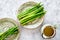 Cooking fresh asparagus. Greens on plate near a jug of oil on grey stone background top view