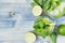 Cooking fresh cold summer beverage mojito with lime, leaf mint, straw, ice cubes, soda on blue wood background, top view, border.