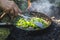 Cooking fried onions in a vintage iron skillet over a burning fire. Cooking at the suburban area. Close-up