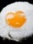 Cooking frying egg with heart shape yolk on black