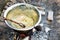 Cooking goulash or stew outdoors in cast-iron cauldron.