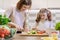 Cooking healthy home meal by family. Mother and daughter cut vegetables at home in the kitchen for salad