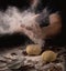 Cooking, kneading dough. Male hands sift flour onto the dough on a dark background