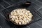 Cooking Manti Dumpling, raw food in a steel tray. Black background. Top view