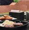 Cooking minced beef burger on cast iron grill skillet outdoors, red meat on frying pan, grilling food in the garden