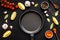 Cooking mockup. Frying pan among spices and vegetables on black desk top-down copy space