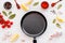 Cooking mockup. Frying pan among spices and vegetables on white desk top-down copy space
