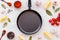 Cooking mockup. Frying pan among spices and vegetables on white desk top-down copy space