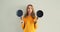 Cooking mood, portrait of happy smiling young woman housewife with empty frying pan on gray wall background