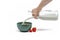 Cooking muesli, isolate on white background Woman pours milk from a jug into a saucer with muesli flakes. Large banner