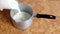 Cooking oatmeal, a woman pours milk into the pan, close-up