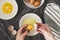 Cooking omlette. Woman& x27;s hands cookingomlette, breaking an fresh egg. Dark background. Food flat lay