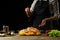 Cooking Peking Duck chef with fruit, on a black background. Horizontal photo, space for menu and design, restaurants, hotel