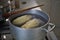 Cooking phase of dumplings in the boiling water set in aged silver aluminum pot on the gas cooker