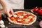 Cooking pizza. Hands adding fresh mushrooms to pizza. Pizza ingredients on the wooden table