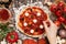 Cooking Pizza. Hands adding ingredients to pizza. Pizza ingerdients on the wooden table, top view