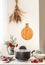 Cooking pot with breakfast porridge on kitchen table with  berries, plates, flowers and bowls at wall background with wooden