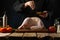 Cooking poultry dishes. The chef sprinkles spices on turkey and chicken. Ingredients on a simple wooden table. Dark background.