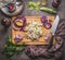 Cooking preparation with vegetables: kohlrabi and leeks on wooden cutting board with knife on rustic background, top view. Healthy