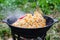 Cooking rice pilaf in a large cast-iron pot on fire