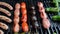 Cooking sausages on barbeque grill. Different types. A sausage is getting turned on a grill. Close-up shot.