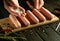 Cooking sausages. A chef hand adds dry spices to Munich sausages on a kitchen board before grilling