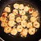 Cooking shrimps in a black pan