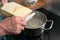 Cooking spaetzle, hands of a man are scraping  homemade egg pasta dough from a wooden board into boiling water, typical dish in