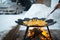 Cooking and stirring potatoes in a flat pan on the bonfire outdoor of winter