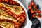 Cooking in tomatoes monkfish fish in a baking dish. Fresh seafood. Gray background. Top view