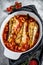 Cooking in tomatoes monkfish fish in a baking dish. Fresh seafood. Gray background. Top view