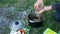 Cooking in the tourist camp. A man pours a pack of beans into a pot