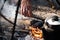 Cooking on touristic campfire. Smoked kettle and male hand throwing firewood into the fire. Touristic life concept
