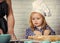 Cooking training. Child cook in chef hat helping mother