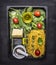 Cooking and vegetarian concept pasta with cheese, colorful spices, herbs, butter and a small grater in a black wooden tray on wood