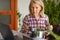 Cooking woman looking at computer while preparing food in kitchen. Beautiful mature woman reading cooking recipe